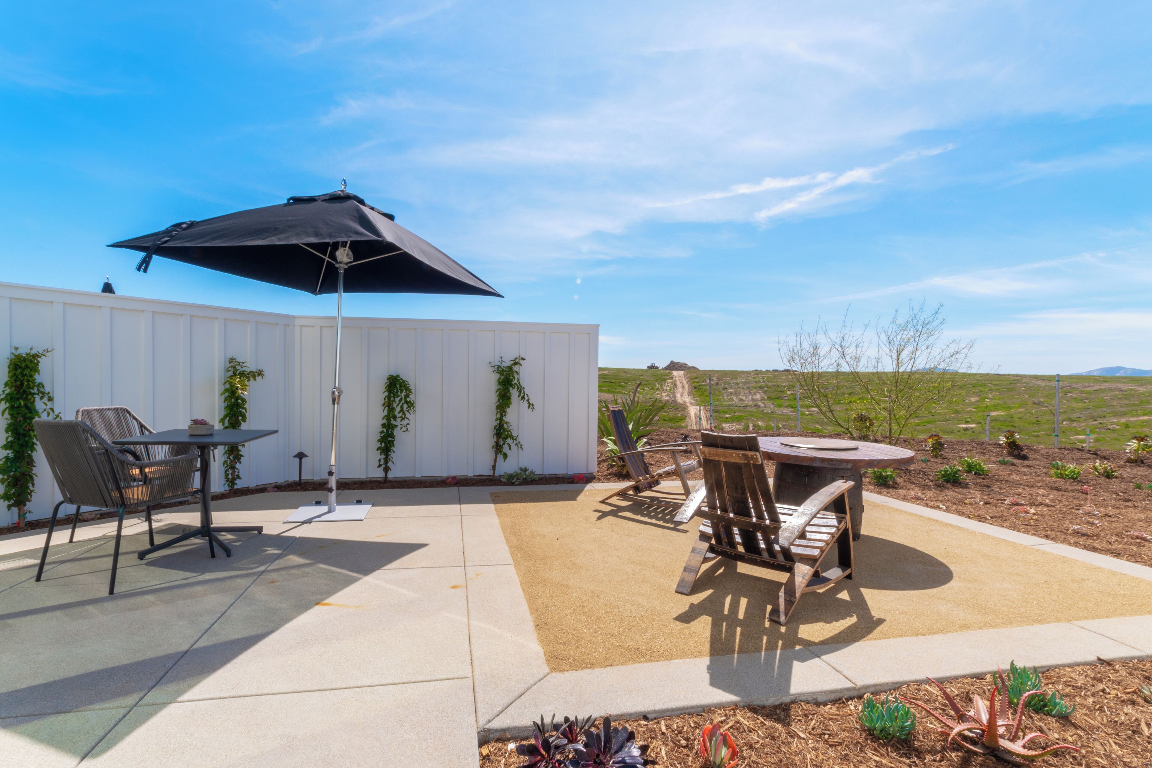 Une terrasse avec une table et des chaises, un parasol et une vue sur la campagne.