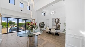 A spacious room with a glass table, a dining area with chairs, and a view of an outdoor pool. - The New Inn (Temecula)