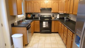 A kitchen with wooden cabinets, a black stove, and a stainless steel refrigerator. - Fun and walkable area, sleeps 9, private parking and patio, newly renovated! (St. Louis)