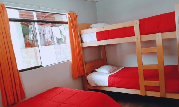 Une chambre avec un lit superposé, une fenêtre et des rideaux orange.