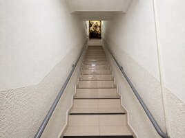 Una escalera con peldaños color beige y barandilla, que conduce a una habitación con un cuadro en la pared.