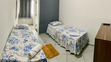 A room with two single beds, a wooden desk, and a small rug.
