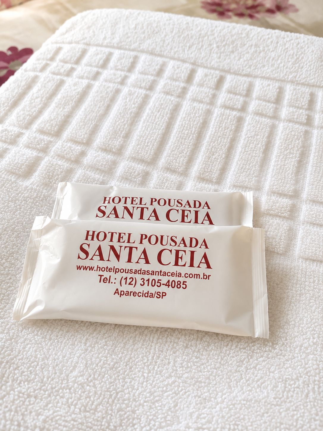 Two white hotel welcome bags on a textured white surface.