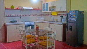 A compact kitchen with a stove, sink, refrigerator, and a dining table with chairs. - CASA GRAU, with 4 rooms with own bathroom, comfortable, central and safe. (Tarapoto)