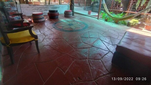 A covered outdoor seating area with a patterned floor, a hammock, and a stack of tires. - CASA GRAU, with 4 rooms with own bathroom, comfortable, central and safe. (Tarapoto)