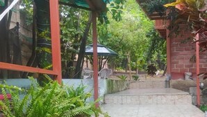 A covered outdoor area with steps leading up to a platform, surrounded by greenery and a brick wall. - CASA GRAU, with 4 rooms with own bathroom, comfortable, central and safe. (Tarapoto)