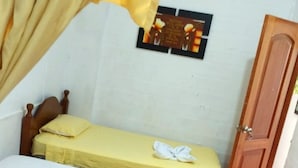 A small, single-room accommodation with a wooden floor, a bed with a yellow bedspread, a bedside table, and a curtain. - CASA GRAU, with 4 rooms with own bathroom, comfortable, central and safe. (Tarapoto)