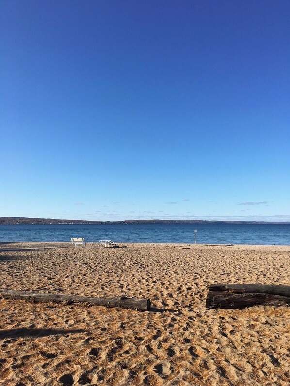 A beach with a clear sky, a sandy shore, and a calm sea. - Brand New Waves of Blue Welcomes You! (Traverse City)