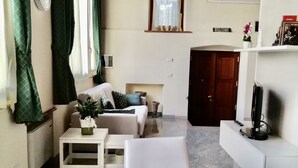 Un salon chaleureux avec un canapé, une table basse et un coin repas comprenant des chaises et un chemin de table à motifs.