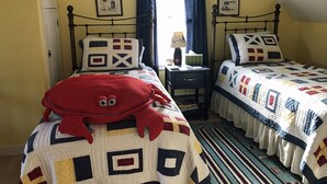 Una camera da letto con due letti, un comodino, una lampada e un peluche rosso.