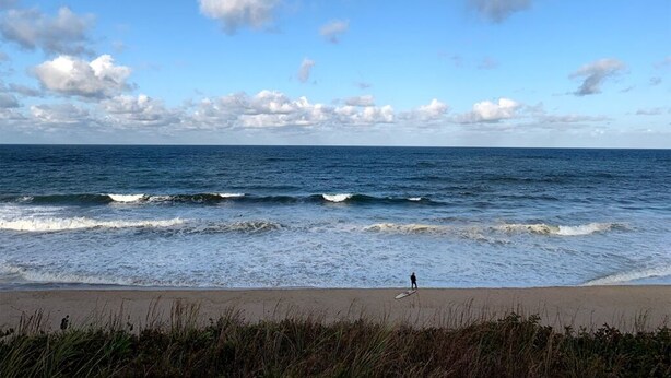 Una spiaggia con onde e una persona che fa surf.
