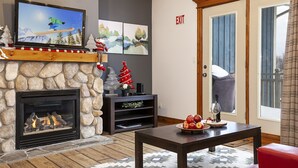 Ein gemütlicher Wohnbereich mit Kamin, Fernseher und einem kleinen Weihnachtsbaum.