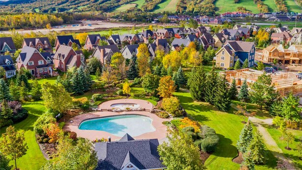 Ein Wohngebiet mit Häusern, einem Schwimmbad und einer hügeligen Landschaft im Hintergrund.