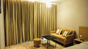 Habitación de hotel con sofá, reposapiés y una pequeña mesa.