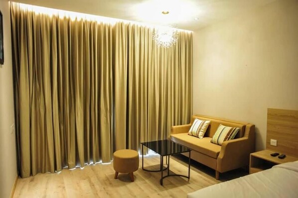 A hotel room with a sofa, ottoman, and a small table.