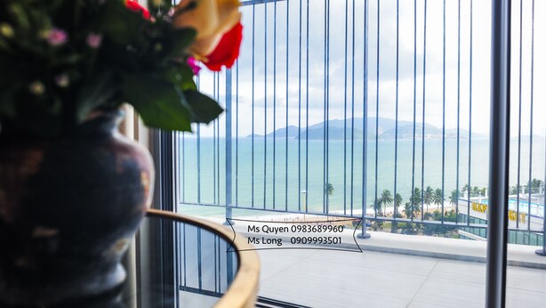 Un balcón con vistas al mar y las montañas, una planta en maceta con flores, e información de contacto para la Sra. Quyen y la Sra. Long.