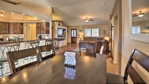 Un comedor amplio con una mesa y sillas de madera, una cocina al fondo y una sala de estar con sofá y televisor.