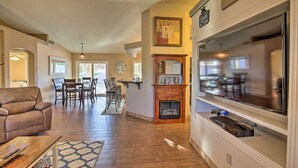 Una sala de estar amplia con chimenea, un televisor grande y un comedor con sillas y una mesa.