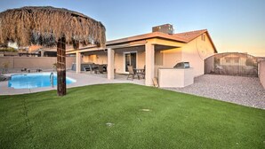 Una casa moderna con piscina, mobiliario exterior y un gran árbol.