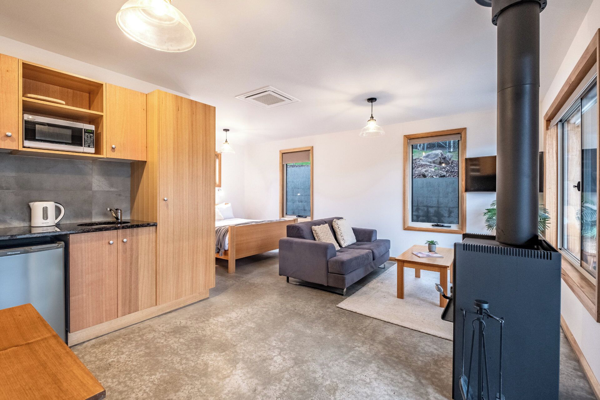 A compact living space with a kitchenette, a sofa, a dining area, and a large window.