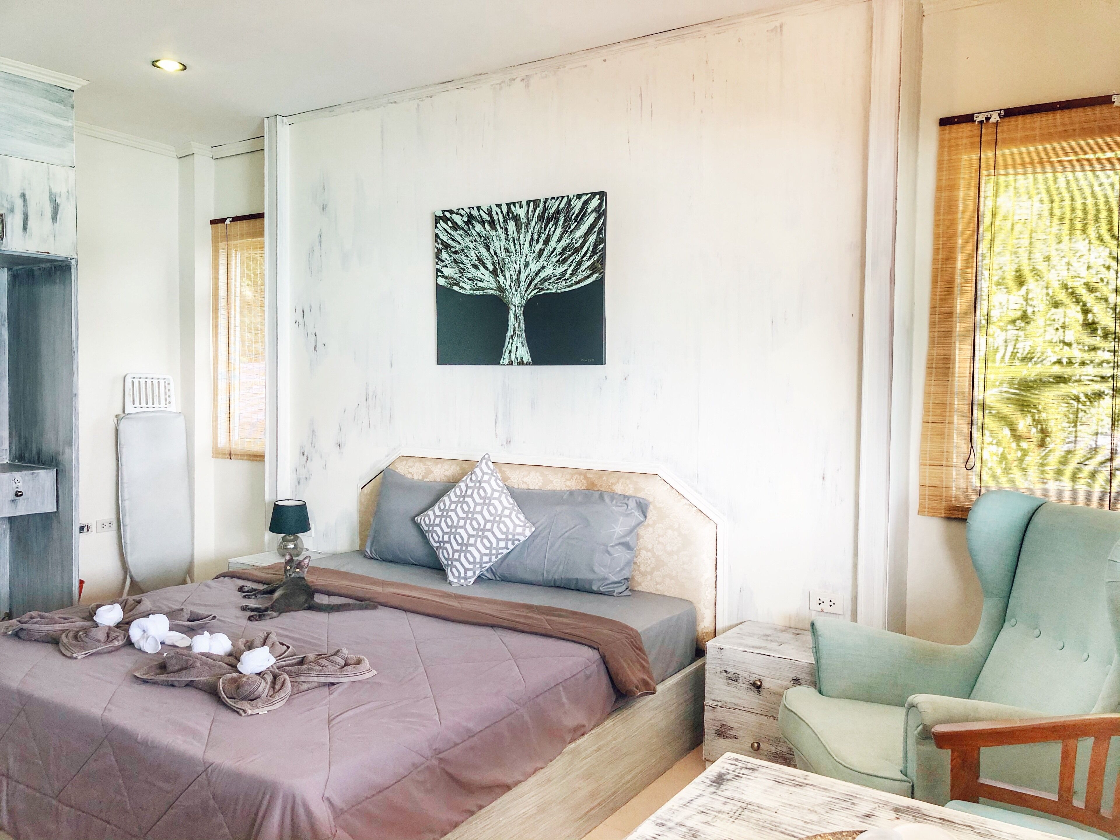 Un dormitorio con cama, una silla, mesita de noche, radiador y ventana con persianas.