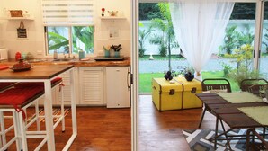 Una cocina con ventana, un comedor con mesa y sillas, y vista a un jardín.