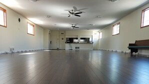 Un'ampia stanza con pavimenti in legno, una ventola a soffitto e grandi finestre.