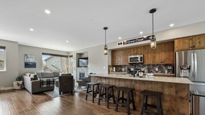 Eine moderne Küche mit Holzausstattung, Edelstahlgeräten und einer Bar mit Hockern.