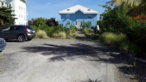 A blue house with a white roof, surrounded by greenery and a gravel path. - Comfy Villa Suites in Long Bay Beach (Long Bay Hills)