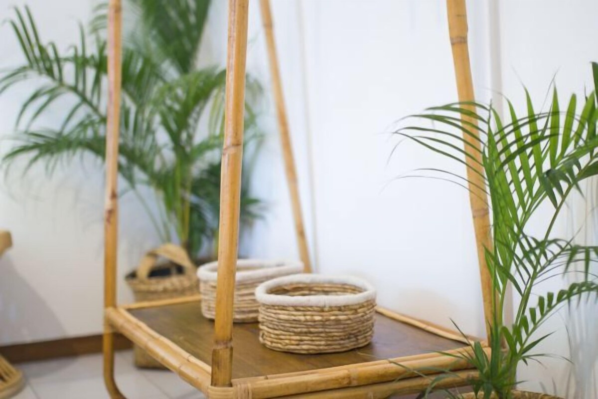 A room with a bamboo-framed mirror, wicker baskets, and green plants.