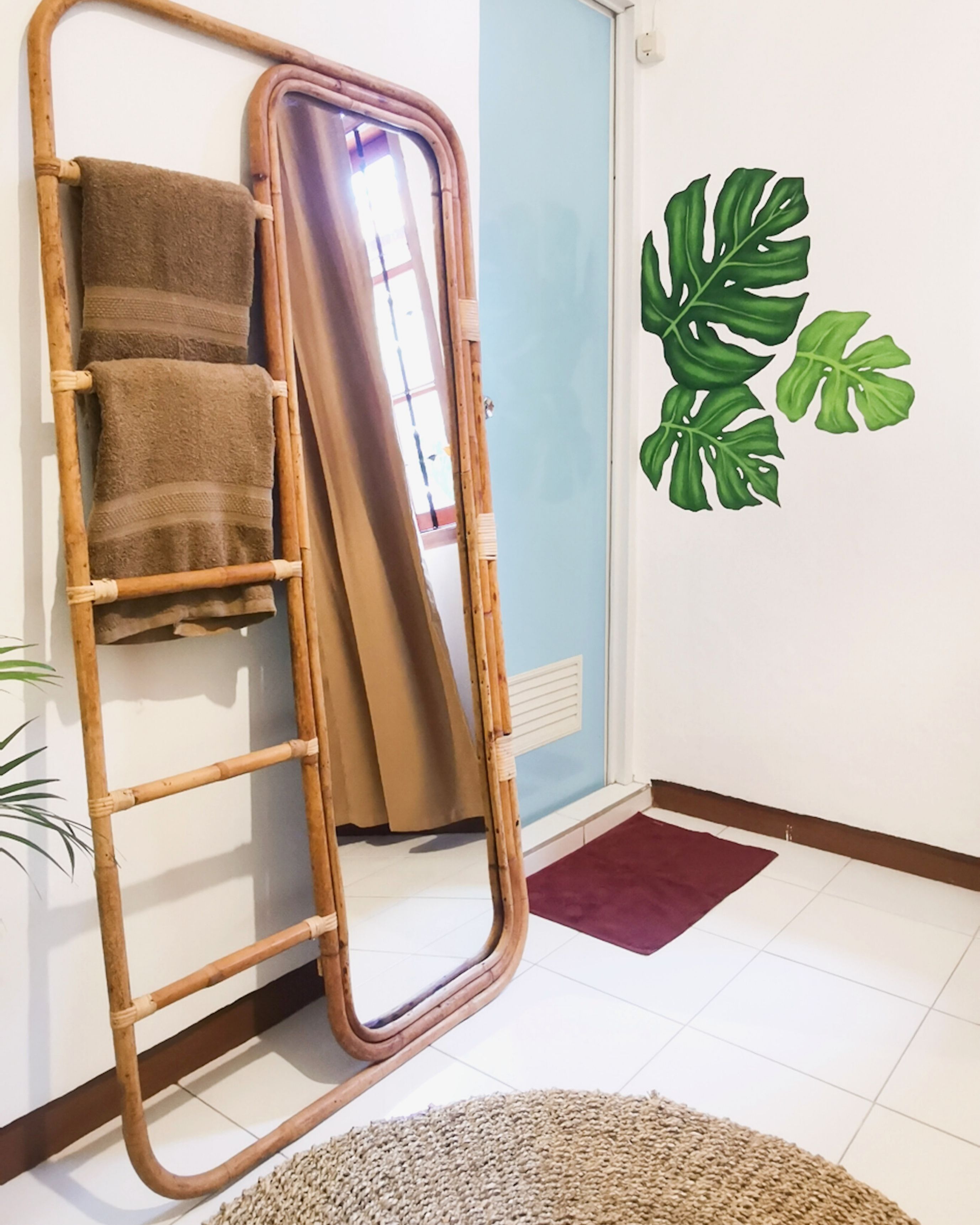 A room with a bamboo ladder leaning against a wall, a large mirror, and a door with a curtain.