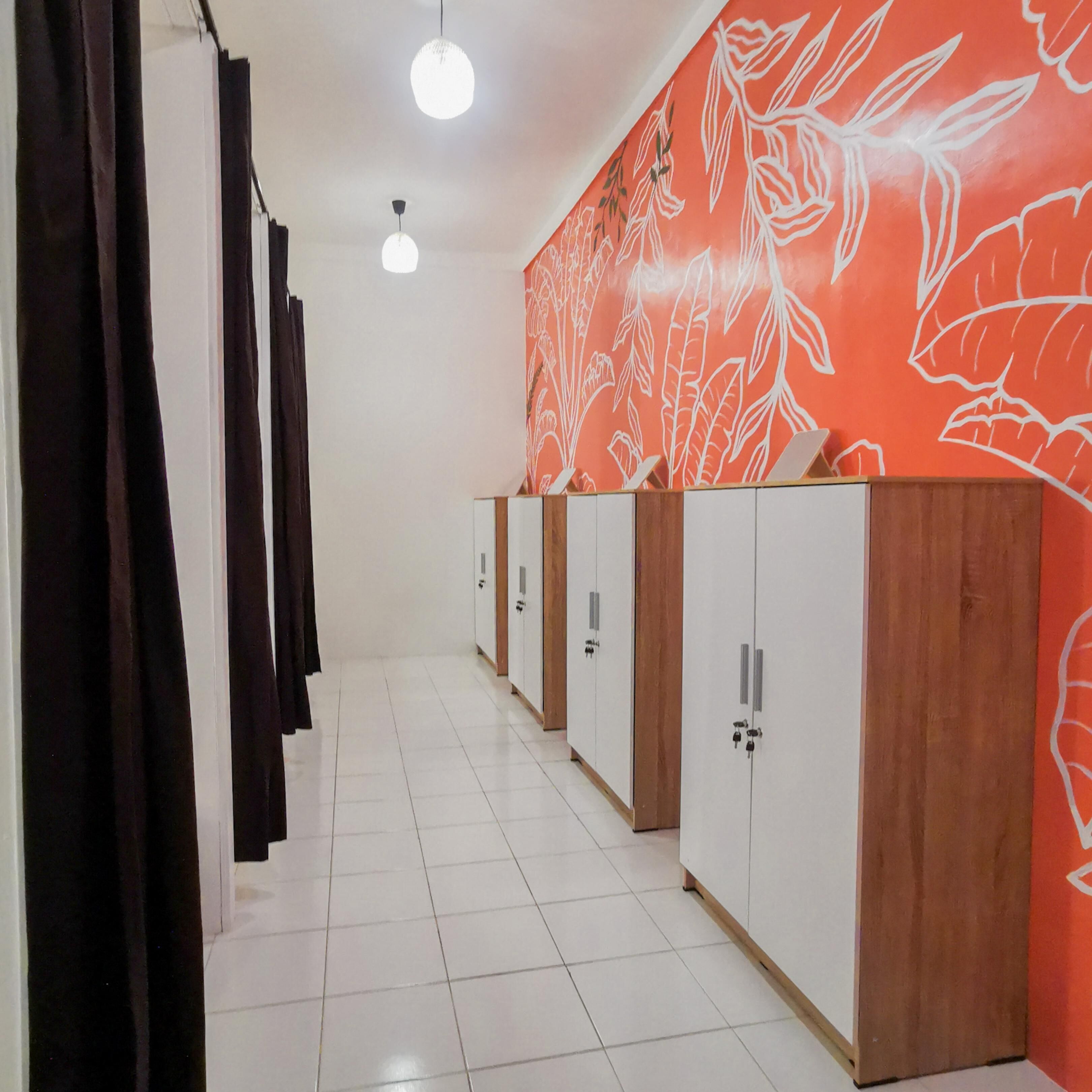 A hallway with lockers, a tiled floor, and a wall with a leaf pattern.