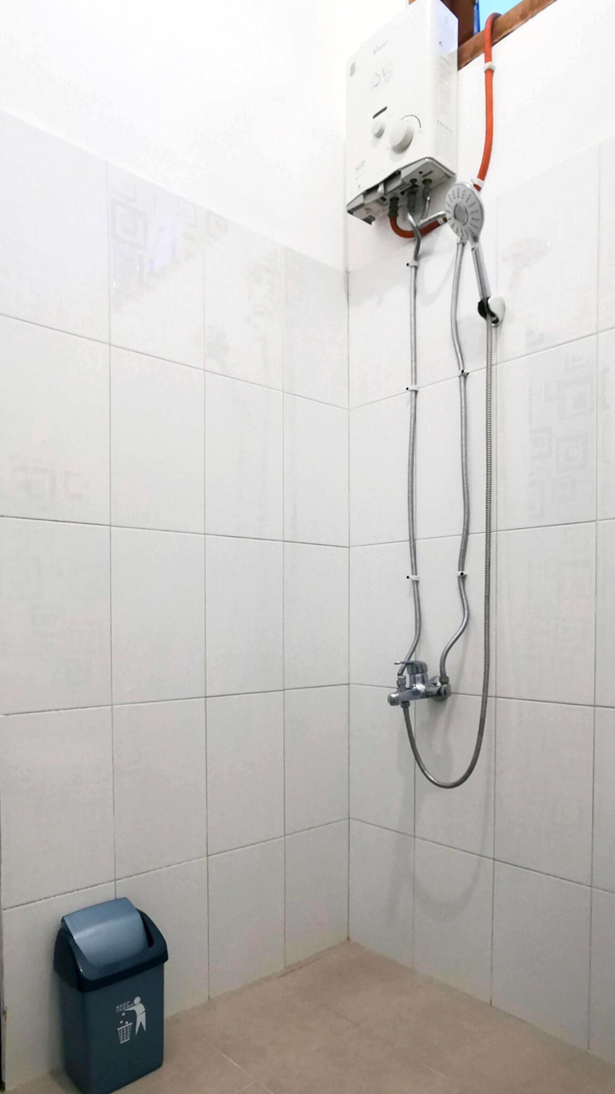 Ducha con cabezal de ducha de mano y panel de control en la pared.