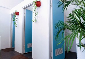 A hallway with blue doors, potted plants, and a large green plant in the corner.