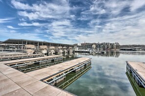 A marina with docked boats, a large building with a sign, and a calm water body. - Getaway w/ Hot Tub in Margaritaville Lake Resort! (Osage Beach)