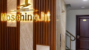 A reception area with a wooden panel design and a sign that reads "Moschino.it". - Moschino HT (Nha Trang)