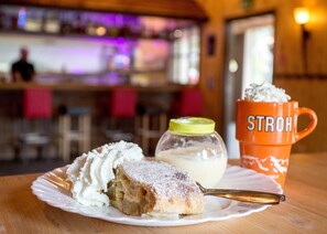 Un plato de postre con un pastel y una taza con la etiqueta "STROH" sobre una mesa de madera.