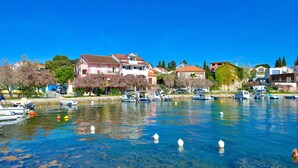Un port de plaisance avec des bateaux amarrés, une eau claire et des maisons le long de la côte.