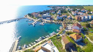 Vue aérienne d’une ville côtière avec un port de plaisance, des immeubles résidentiels et une vue dégagée sur la mer.