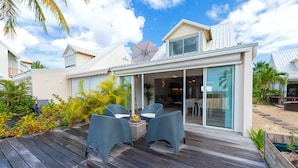 Una casa moderna con una terraza, muebles de exterior y un amplio ventanal corredizo que da a un patio.