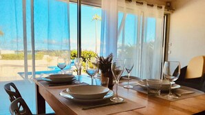 Una mesa de comedor dispuesta con platos, vasos y cubiertos, ubicada cerca de una ventana con vistas al exterior.