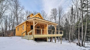 A wooden cabin with a covered porch and a staircase leading to the entrance. - Newly Built Cabin w/ Hot Tub - 16 Mi to Stowe Mtn! (Morristown)