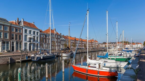 A canal with boats docked along the side, surrounded by traditional buildings with red-tiled roofs.