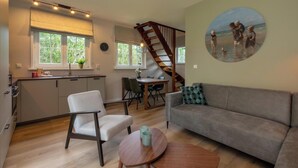 A modern living room with a sofa, a dining table, and a kitchen area with a staircase.