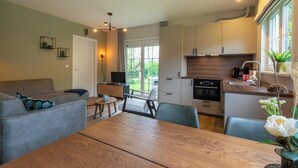 A compact living space with a dining area, kitchenette, and a large window providing natural light.