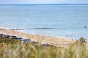 Ein Strand mit einer Reihe von Gebäuden, einem Wellenbrecher und freiem Blick auf das Meer.
