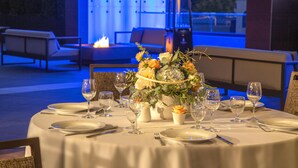 A table set for dining with a vase of flowers, wine glasses, and plates. - Hilton Garden Inn Redmond Seattle (Redmond)