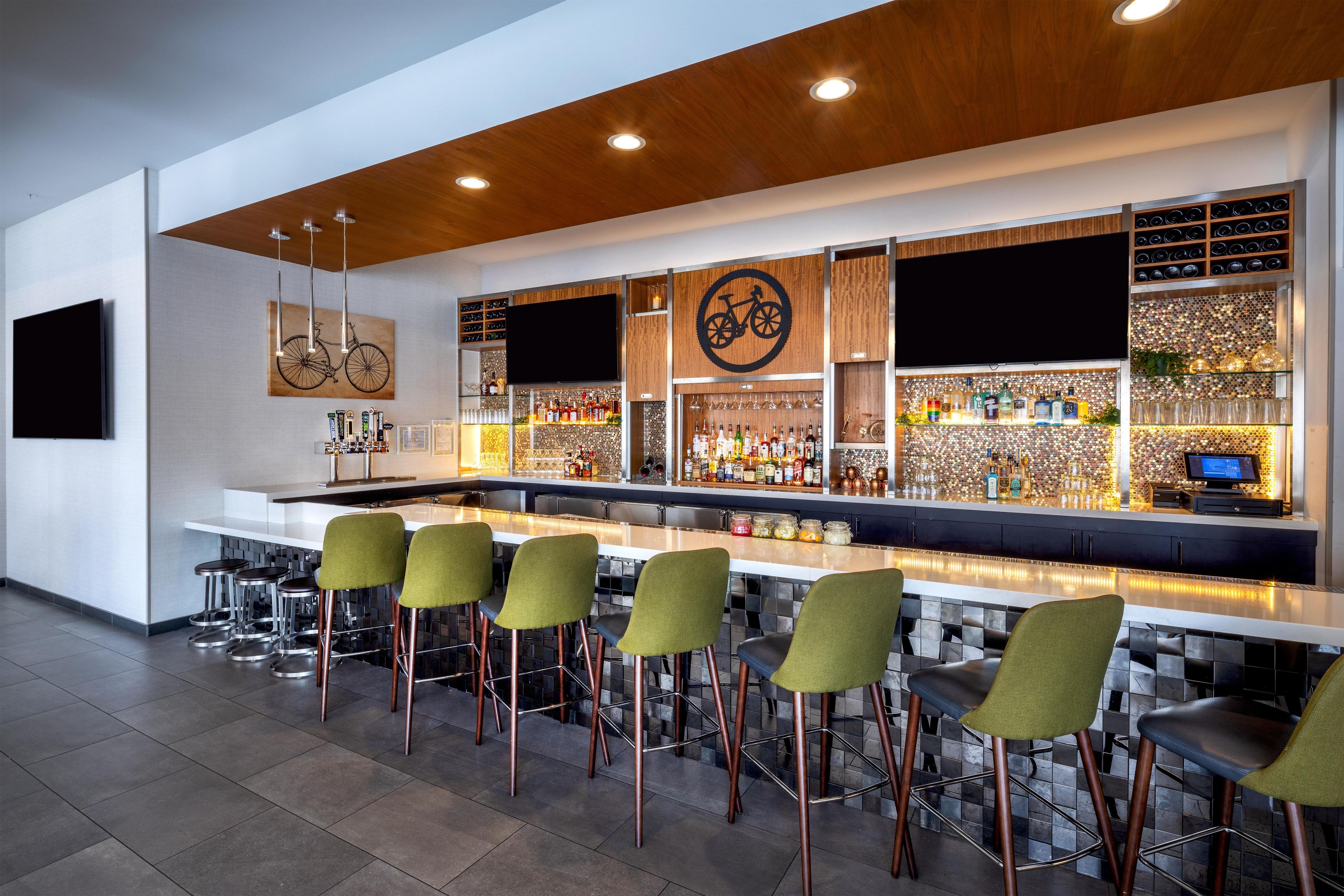Eine Bar mit einer langen Theke, mehreren Hockern und einer Auswahl an Flaschen und Gläsern.