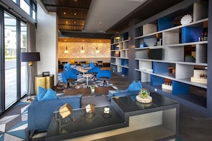 A modern hotel lobby with seating areas, a bar, and a bookshelf. - Hilton Garden Inn Redmond Seattle (Redmond)