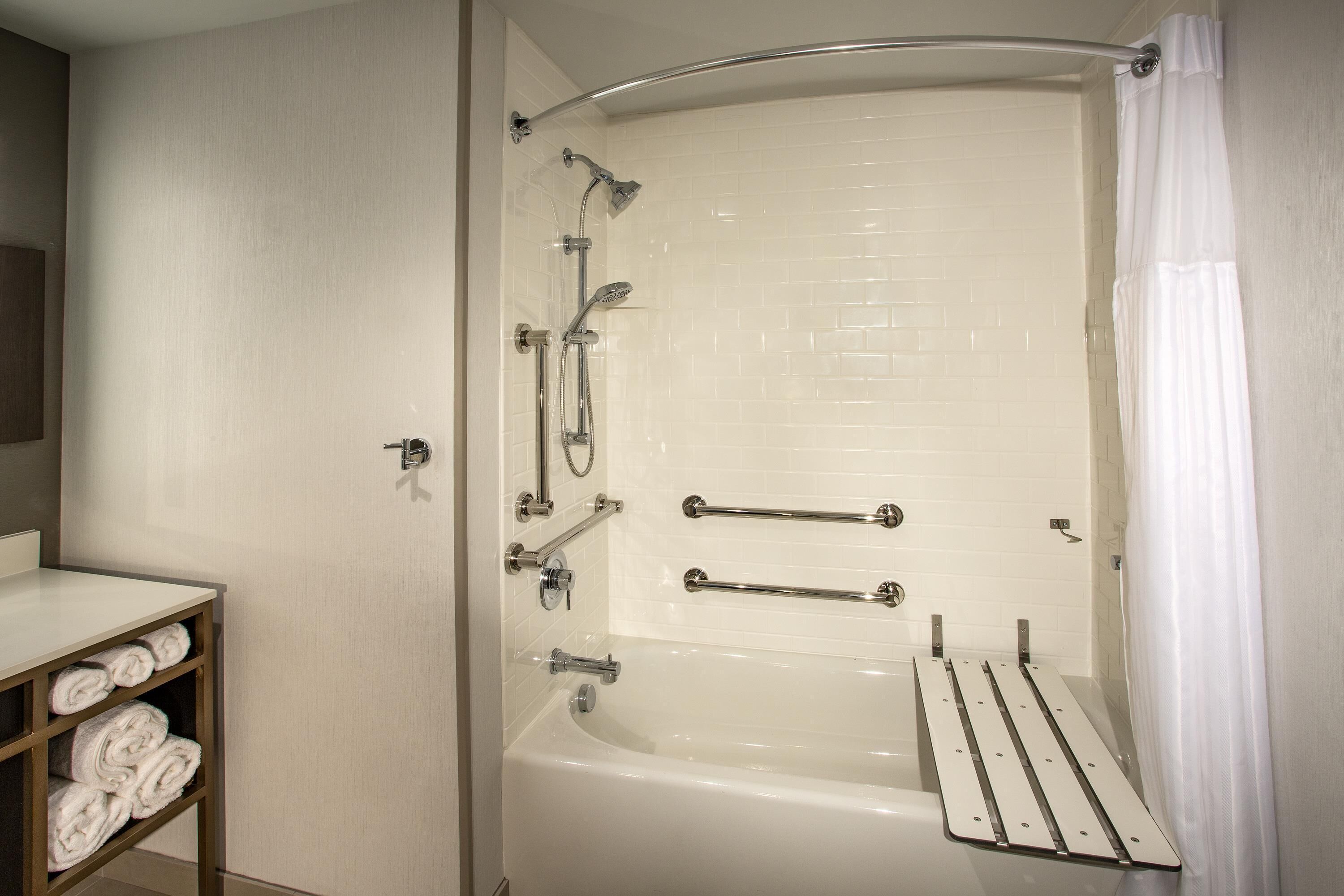 Un baño moderno con bañera, ducha y barras de apoyo.